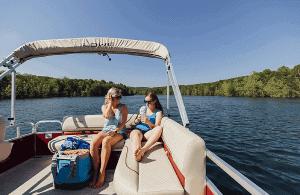 Two women relaxing on Lowe Boats UF162 pontoon boat on a lake.