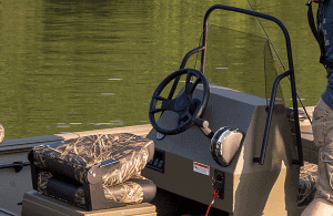 Close-up of boat steering console with camouflage seat and water background.