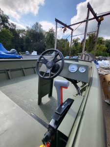 Outdoor boat cockpit with steering wheel, gauges, and control lever at Camp & Cruise.