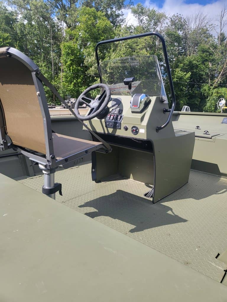 Boat cockpit with steering wheel and control panel in outdoor setting.