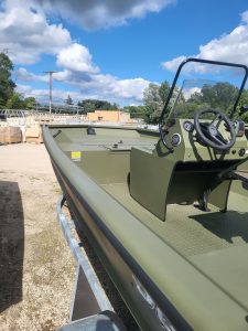 Green boat with steering wheel and windshield on a sunny day.
