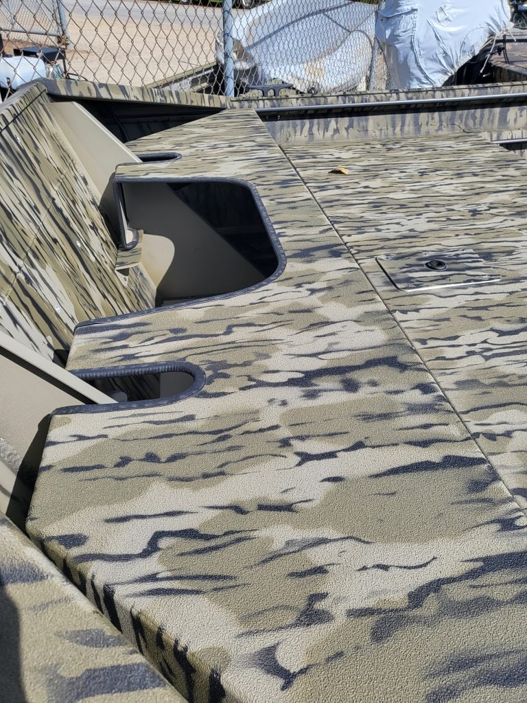 Close-up of camouflage boat deck with textured surface and storage compartments.