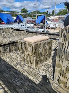 Camouflage boat seating with beige cushion on a boat deck.