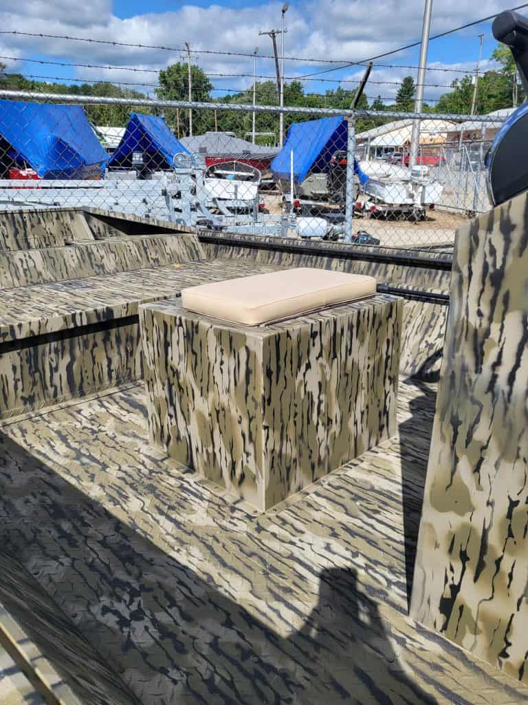 Camouflage boat seating with beige cushion on a boat deck.
