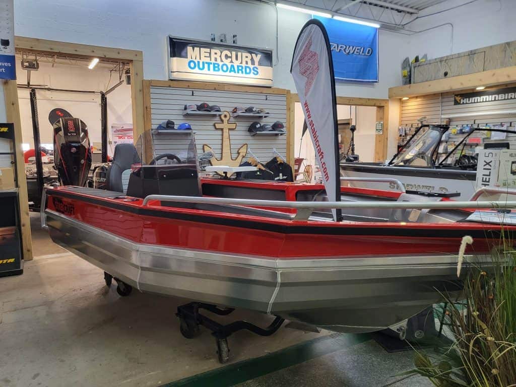 Red and gray StabiCraft 1450 Frontier Sportfish boat on display indoors.