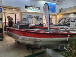 Red and gray StabiCraft 1450 Frontier Sportfish boat on display indoors.