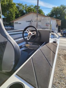 Golf cart interior featuring steering wheel, dashboard, and windshield at Camp & Cruise.