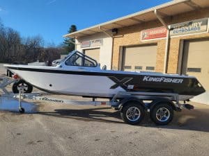 KingFisher 1975 Fastwater X9 boat on trailer outside dealership.