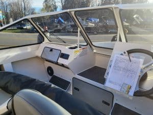 Close-up of the boat's dashboard and steering wheel in bright sunlight.