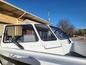 White KingFisher 1975 Fastwater X9 boat parked outside building under clear blue sky.
