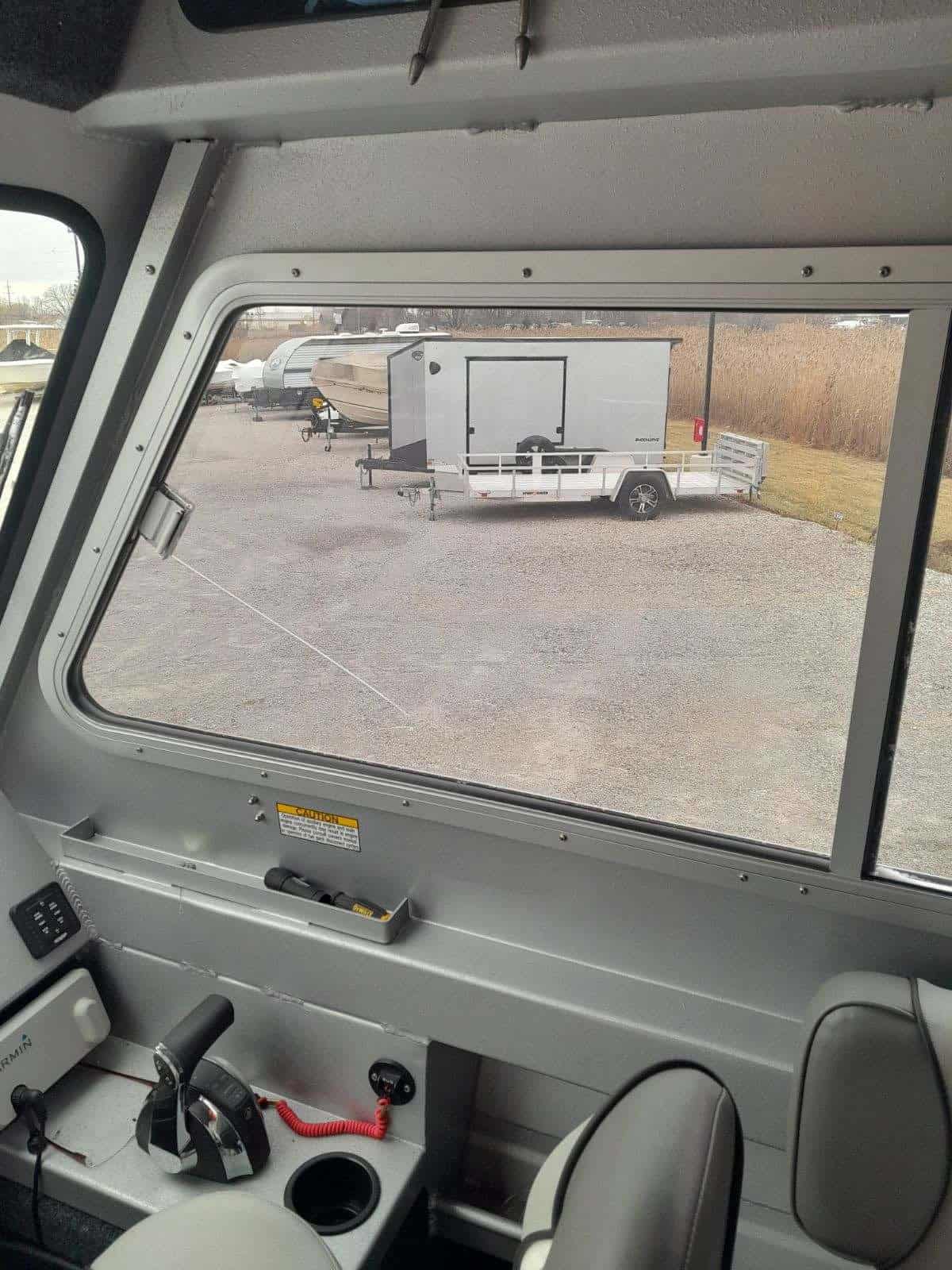 View from inside a utility vehicle showing a trailer and open field.