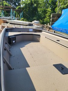 Empty boat deck with storage and control panel in outdoor setting.