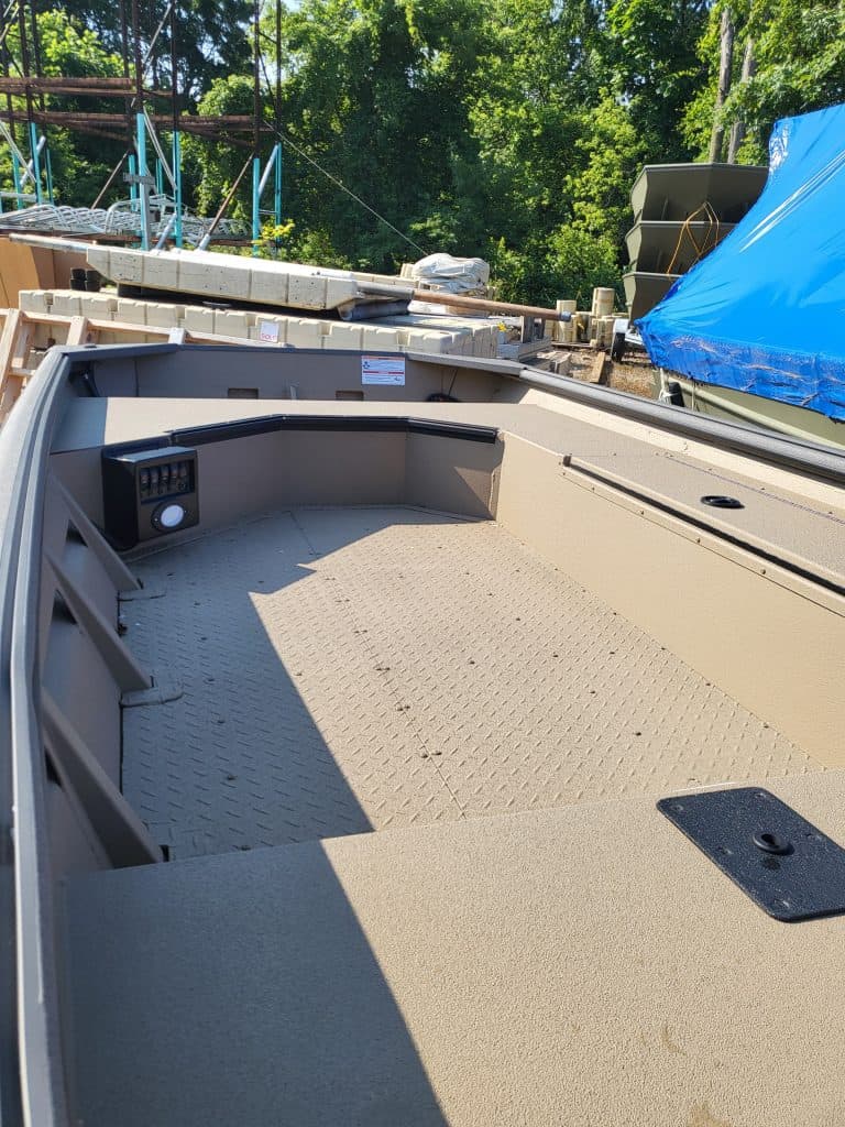 Empty boat deck with storage and control panel in outdoor setting.