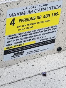 Sign displaying U.S. Coast Guard limits for boat passenger and weight capacity.