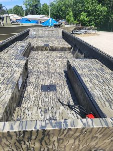 Camouflage boat deck with storage compartments and wiring.