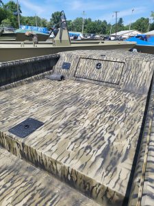 Camouflage boat deck with storage compartments and textured surface.