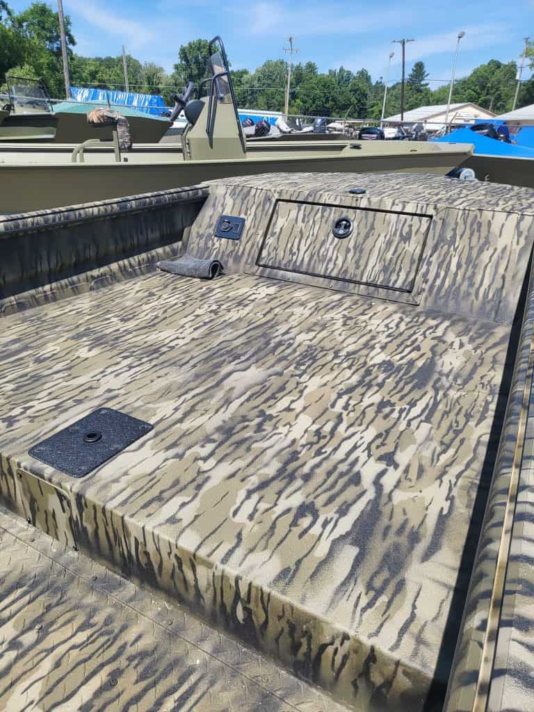 Camouflage boat deck with storage compartments and textured surface.