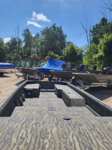 Multiple boats stored outdoors on a sunny day at Camp and Cruise.
