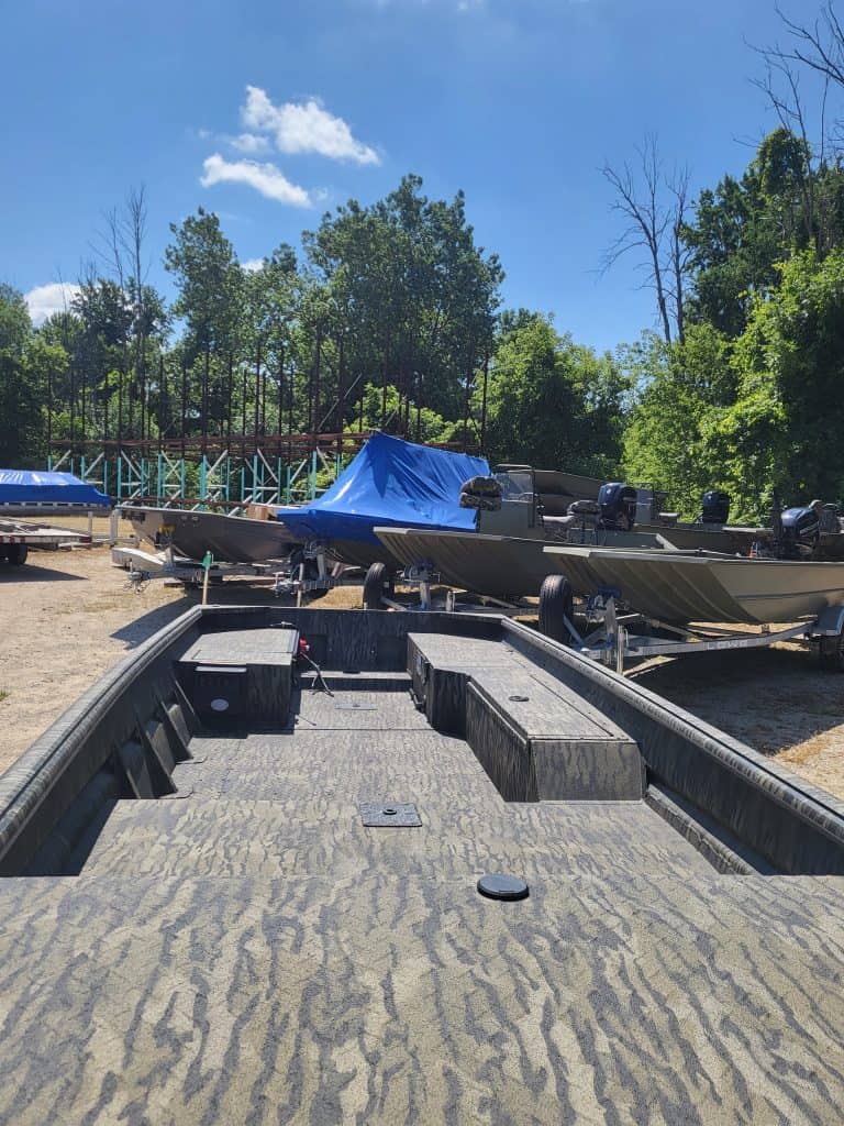 Multiple boats stored outdoors on a sunny day at Camp and Cruise.