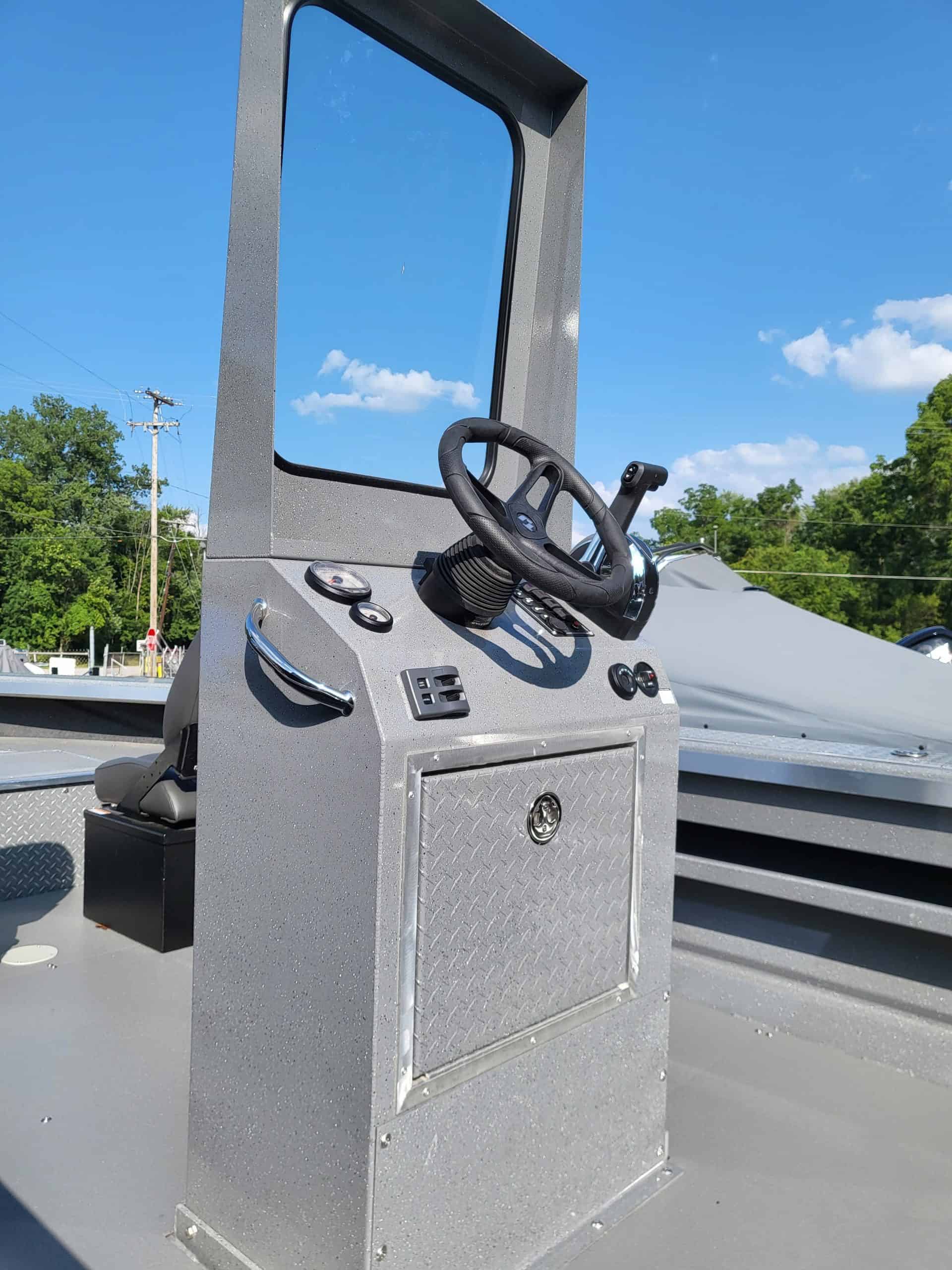 Boat console with steering wheel and controls on a clear day.