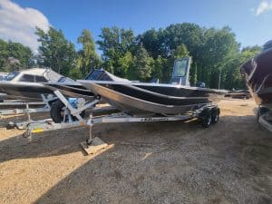 Black and white boat on trailer at boat dealership lot.