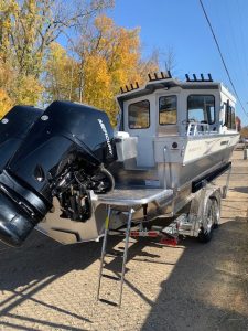 Aluminum boat with outboard motor on trailer, ready for water.