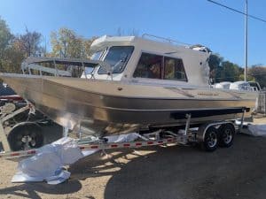 Powerboat on trailer at Camp and Cruise with clear sky and trees in background.
