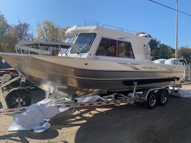 Powerboat on trailer at Camp and Cruise with clear sky and trees in background.