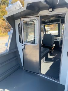 Boat cabin with glass door and interior seating for comfort and safety.