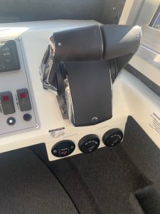 Close-up of boat throttle and control panel with switches and gauges.