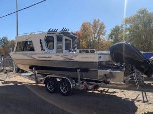 New boat on trailer with outboard motor and cabin, ready for water.