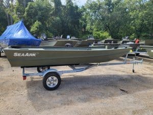 Aluminum fishing boat with trailer at Camp & Cruise, ideal for anglers and outdoor water activities.