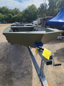A small fishing or utility boat displayed outdoors at Camp & Cruise, ready for sale.