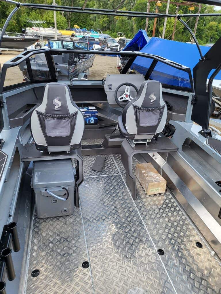 Boat interior with captain and passenger seats, steering wheel, and navigation equipment.