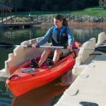 Bright red kayak on the water at Camp & Cruise, with a woman enjoying kayaking activity.