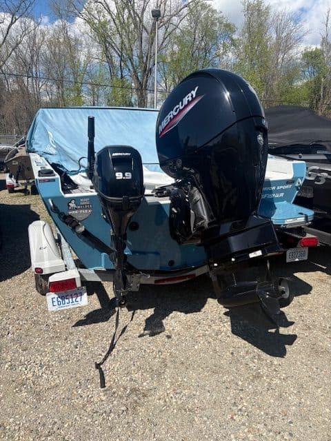 Boat with Mercury 9.9 HP outboard motor at Camp & Cruise, outdoor display.