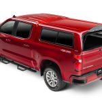 Red Chevrolet Silverado pickup truck with open bed cover, showcasing vehicle accessories and outdoor gear for sale.