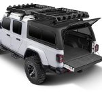 Detailed image of a rugged white Jeep Gladiator with off-road tires, roof racks, and open cargo bed, perfect for outdoor adventures.