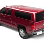 Red Chevrolet Silverado pickup truck with custom camper shell and 4x4 off-road capability.
