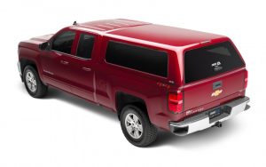 Red Chevrolet Silverado pickup truck with custom camper shell and 4x4 off-road capability.