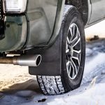 Close-up of SUV tire and wheel on snow, emphasizing winter vehicle preparations and car maintenance.