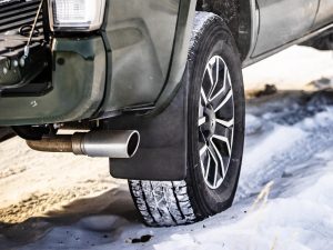 Close-up of SUV tire and wheel on snow, emphasizing winter vehicle preparations and car maintenance.