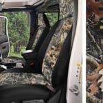 Interior view of a rugged off-road vehicle with camouflage seats in a forest setting.