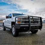 High-resolution image of a white heavy-duty utility truck with grille guard parked outdoors at Camp & Cruise.