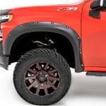 Close-up of a red off-road vehicle showing rugged tire and wheel at Camp & Cruise.