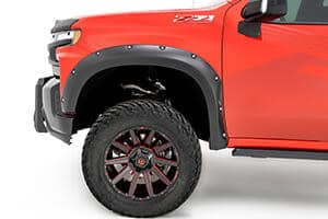 Close-up of a red off-road vehicle showing rugged tire and wheel at Camp & Cruise.
