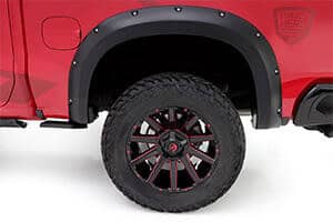 Close-up of rugged off-road tires and black alloy wheels on a red pickup truck.