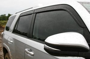 Raindrops on a silver SUV side window after rain at Camp & Cruise dealership.