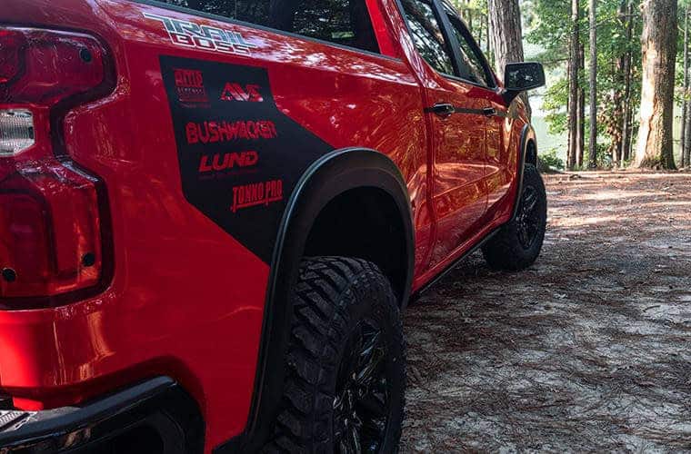 Close-up of a red off-road truck showcasing rugged tires, decals, and outdoor adventure features.