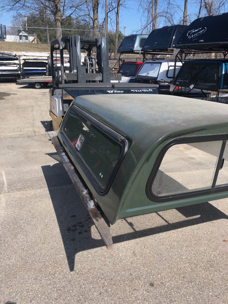 Durable green truck bed with canopy, ideal for outdoor sports equipment storage, on display at Camp & Cruise.